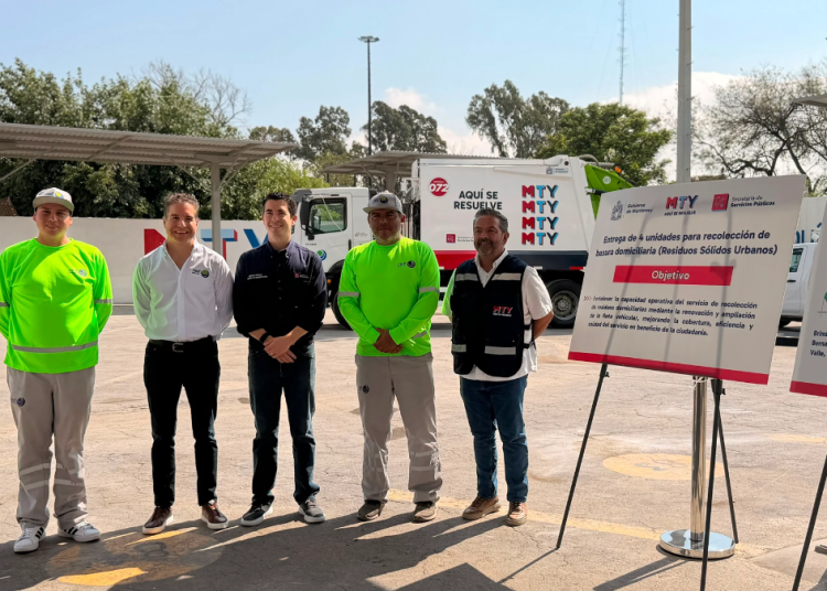 Five Workers in Safety Gear Pose in a Parking Lot Beside Project Boards and a Disposal Truck in the Background, at a Municipal Waste Event. | Tu Colonia Nuevo León