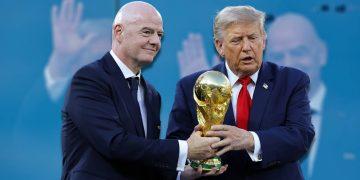 Two Men in Dark Suits Exchange a Large Gold Trophy Against a Blue Backdrop, Hands Clasping the Base. This Image Focuses on the Ceremonial Trophy Transfer. | Tu Colonia Nuevo León