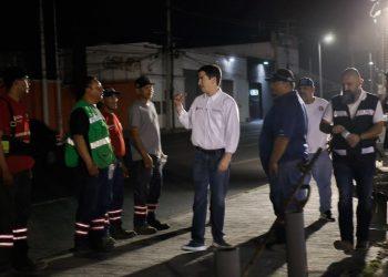 Night Scene of a Man in a White Shirt Talking to a Line of Workers in Reflective Vests and Uniforms on a Street at Night | Tu Colonia Nuevo León